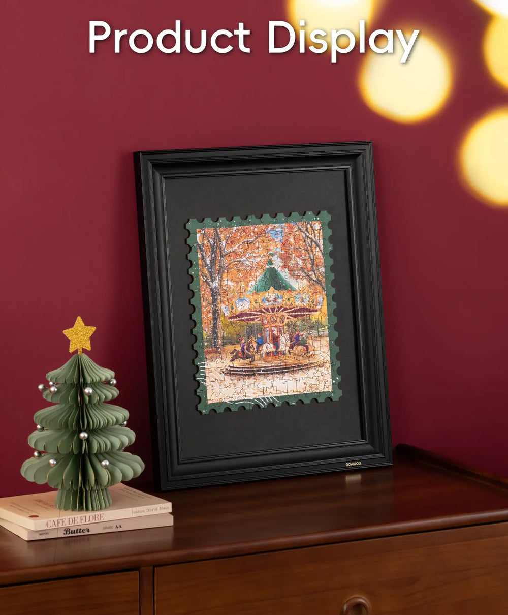 Framed artwork on a wooden surface with a decorative tree and book against a red wall.